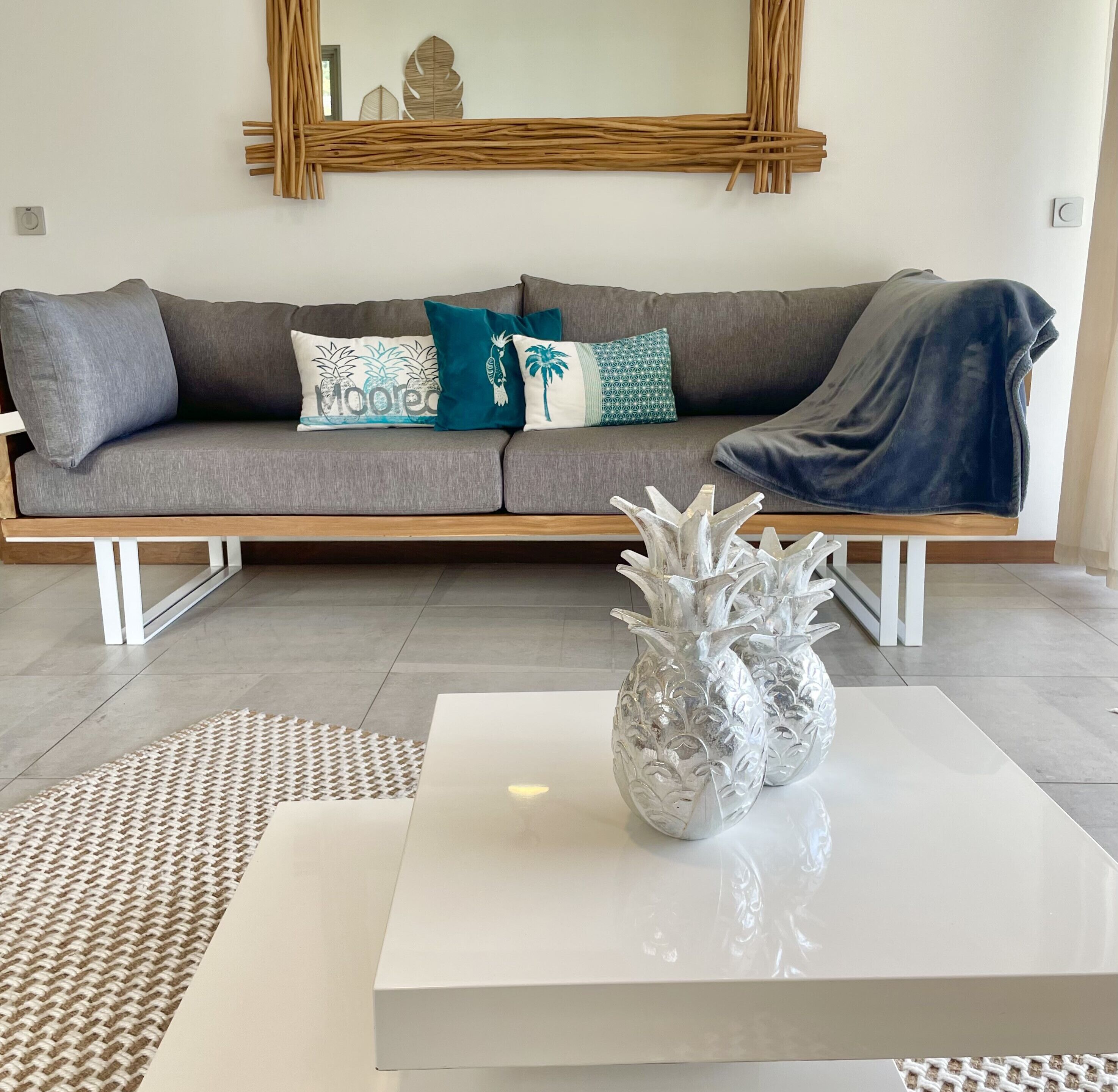 A living room with a grey sofa, decorative pillows, a white coffee table, and a woven rug.