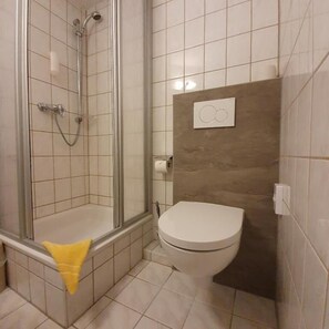Een badkamer met een douchecabine, toilet en handdoekrek.