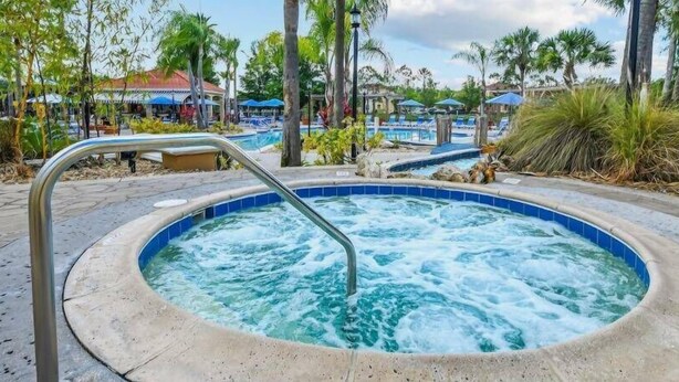 Un bain à remous entouré de palmiers et un espace piscine.