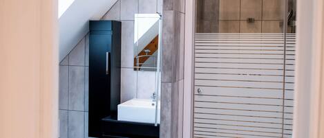 A modern bathroom with a skylight, a walk-in shower, and a tiled floor.