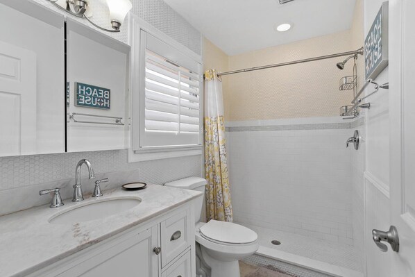 A bathroom with a shower, toilet, and sink. - Naples Park - William Raveis Rentals (Naples)