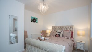 A bedroom with a large bed, a bedside table with a lamp, a mirror, and a framed picture on the wall. - Amazing sea & harbour views of the Moray Firth North Aberdeenshire Scotland. (Macduff)