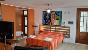 A hotel room with a bed, a television, a painting, and a door. - Le Antiche Colonne (Cinquefrondi)