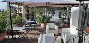 An outdoor patio with round tables and white wicker chairs, surrounded by potted plants and a pergola. - Le Antiche Colonne (Cinquefrondi)