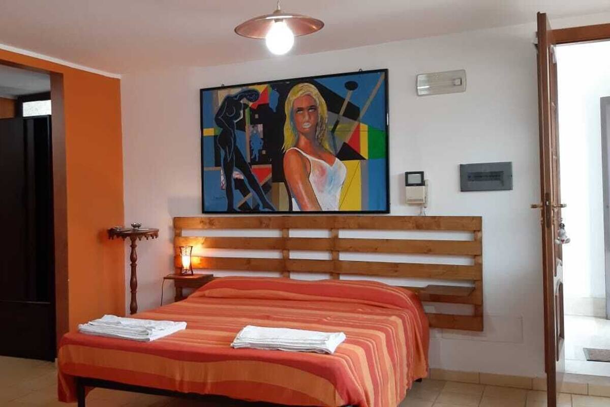 Una habitación de hotel con una cama, un televisor, un cuadro en la pared y una puerta.