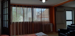 Una habitación con un ventanal grande, un radiador, un sofá y una puerta.