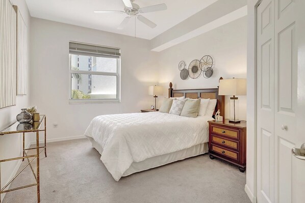 A bedroom with a bed, bedside tables, a nightstand, a ceiling fan, a window with blinds, and a wall with decorative plates. - RELAX, UNWIND, AND ENJOY. (Naples)