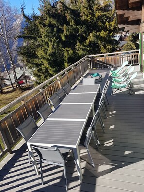 Terrasse bien équipée avec tables, chaises, parasol et chaises longues