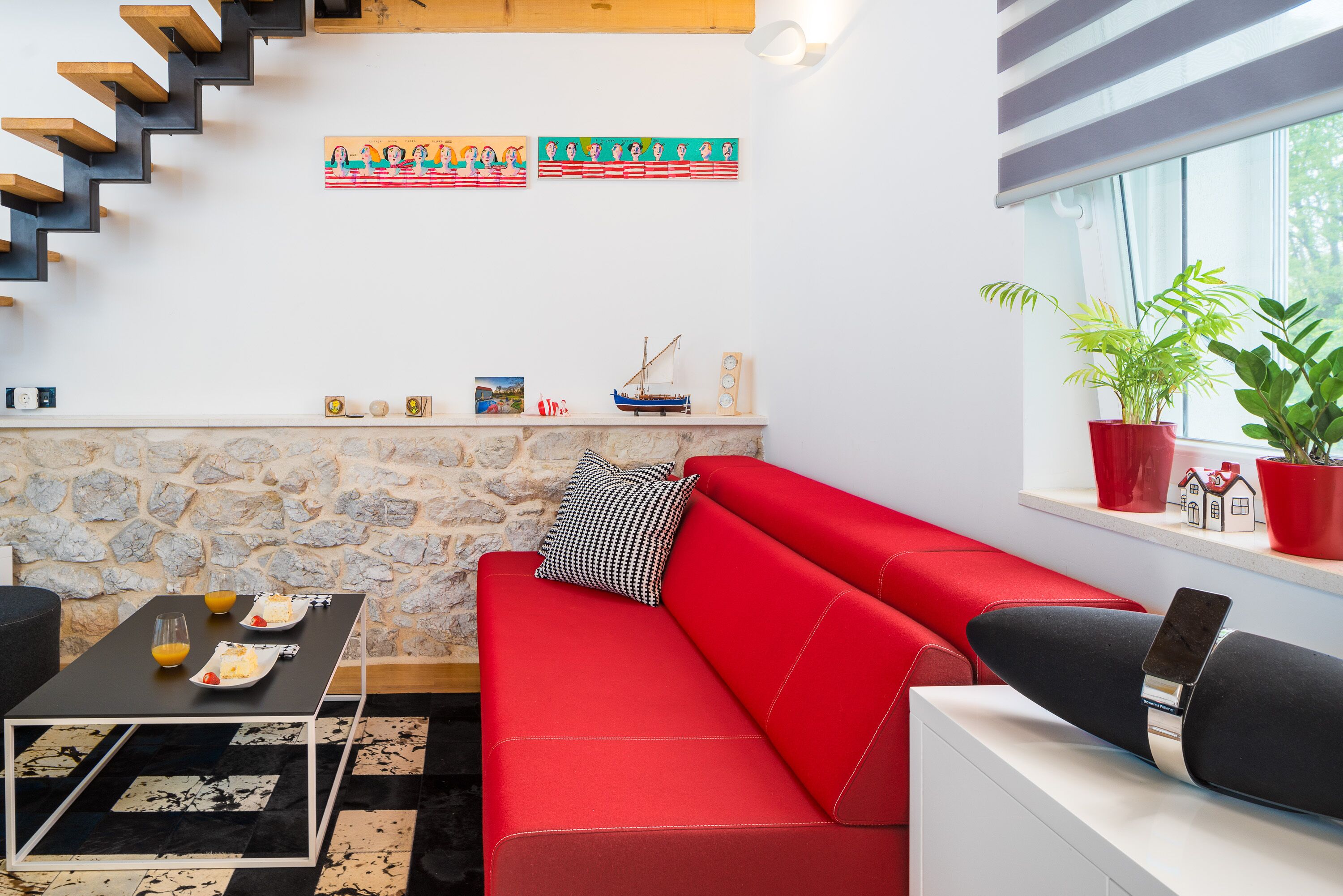 A modern living room with a red sofa, a black coffee table, and a stone wall.