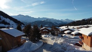 A snow-covered village with wooden buildings, a dirt path, and a mountain backdrop. - Savoie, Col des Saisies, Apartment for rent (Hauteluce)