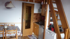 Ett kompakt kök med träskåp, en inbyggd mikrovågsugn och en diskmaskin.