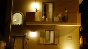 A two-story building with a balcony, a door, and potted plants. - Aramoni B&B (Zambrone)