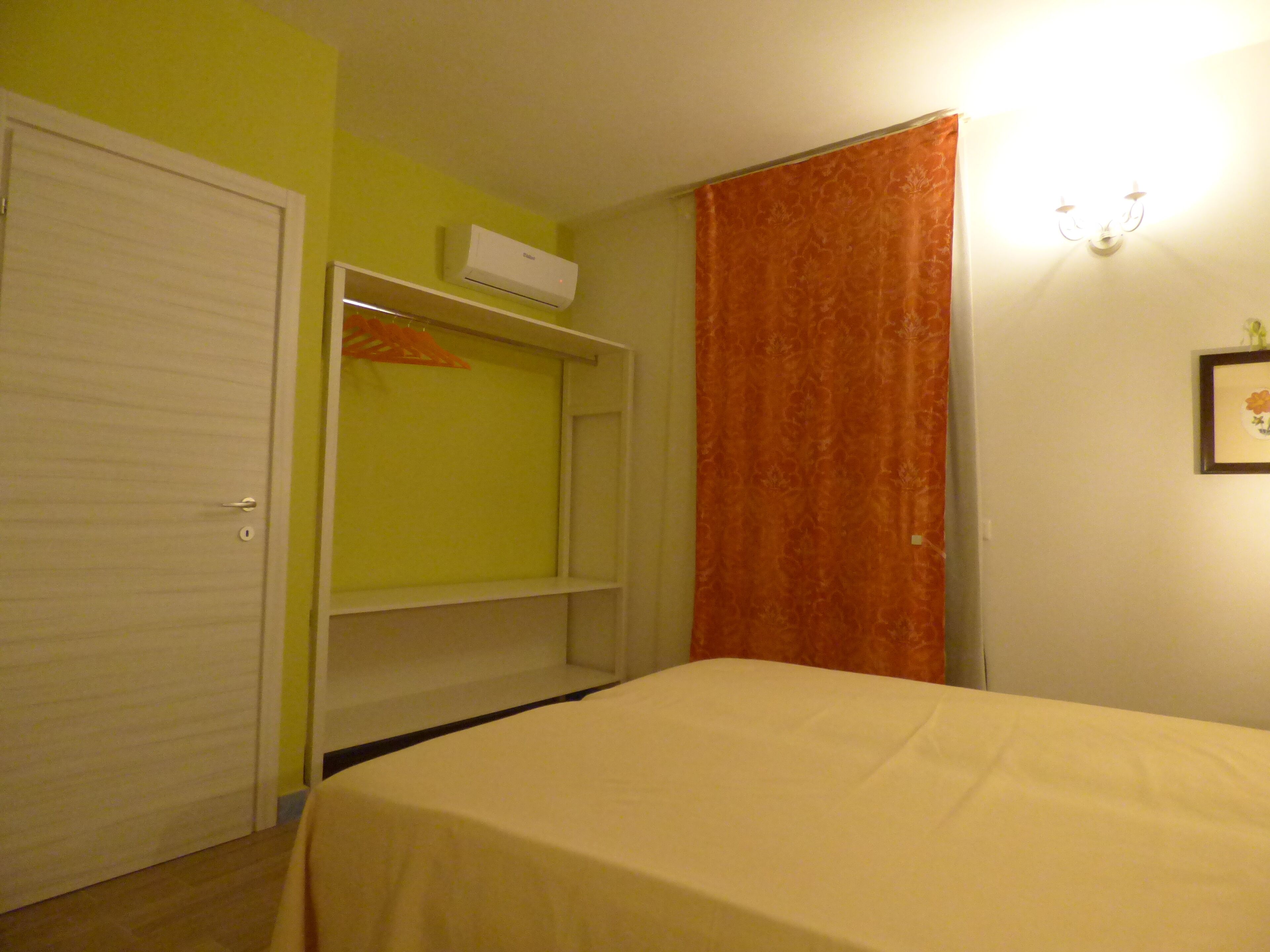 A bedroom with a bed, a wardrobe, and a shelf unit.
