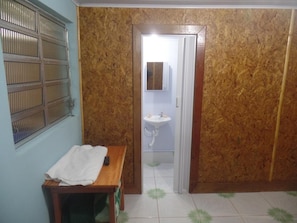 A bathroom with a wooden bench, a sink, and a window with metal bars. - Pousada Ferreira's (Santo André)
