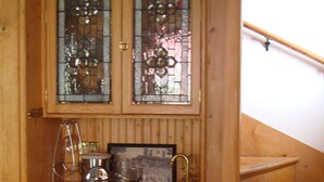 A wooden cabinet with two glass doors, a coffee maker, and a framed picture on the countertop. - Lake Chautauqua Victorian (Dewittville)