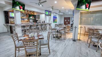 A restaurant with multiple tables and chairs, ceiling fans, and televisions displaying golf scenes.