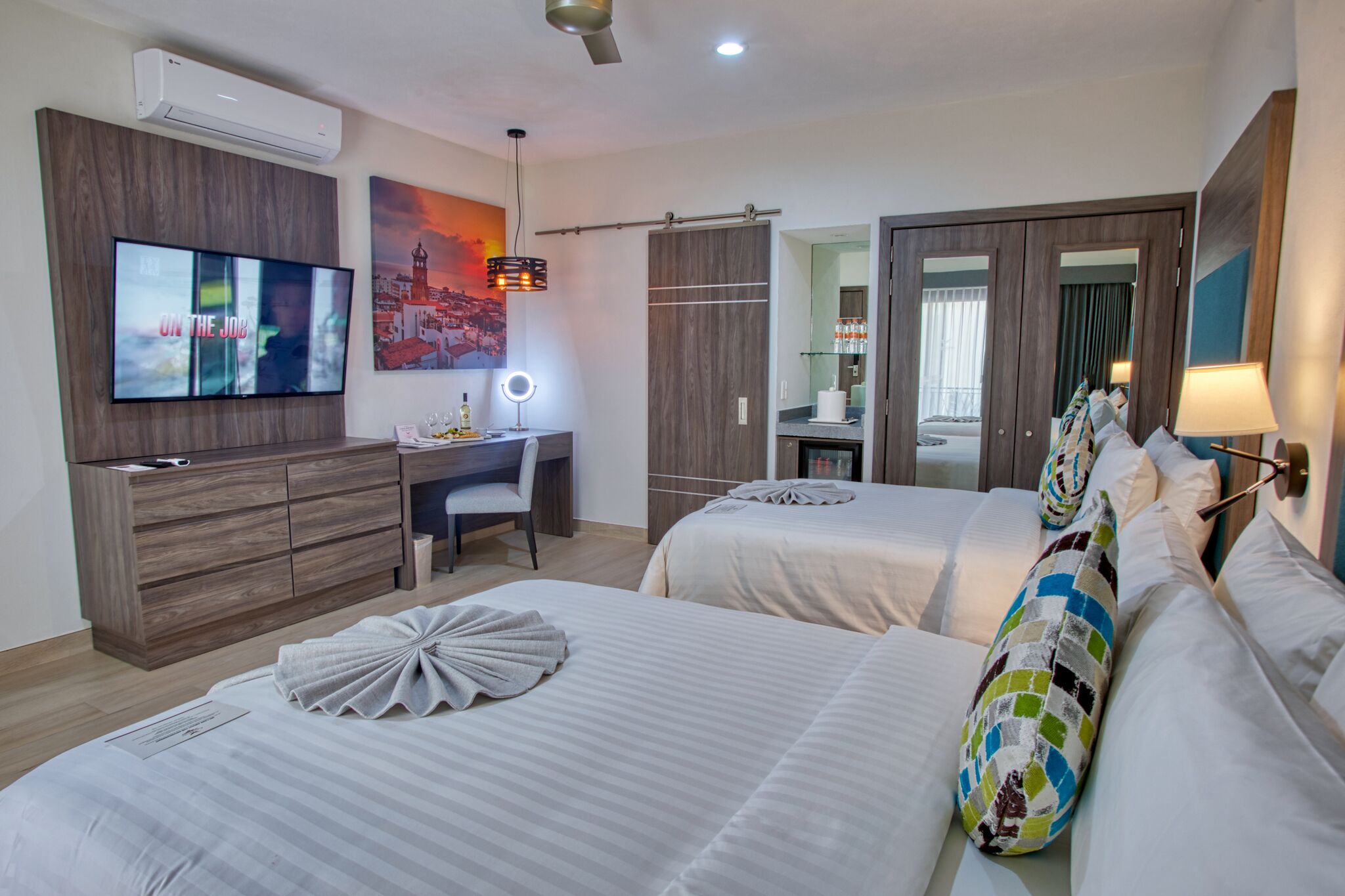 Ein Hotelzimmer mit zwei Betten, einem Schreibtisch, einem Fernseher und einem durch eine offene Tür einsehbaren Badezimmer.
