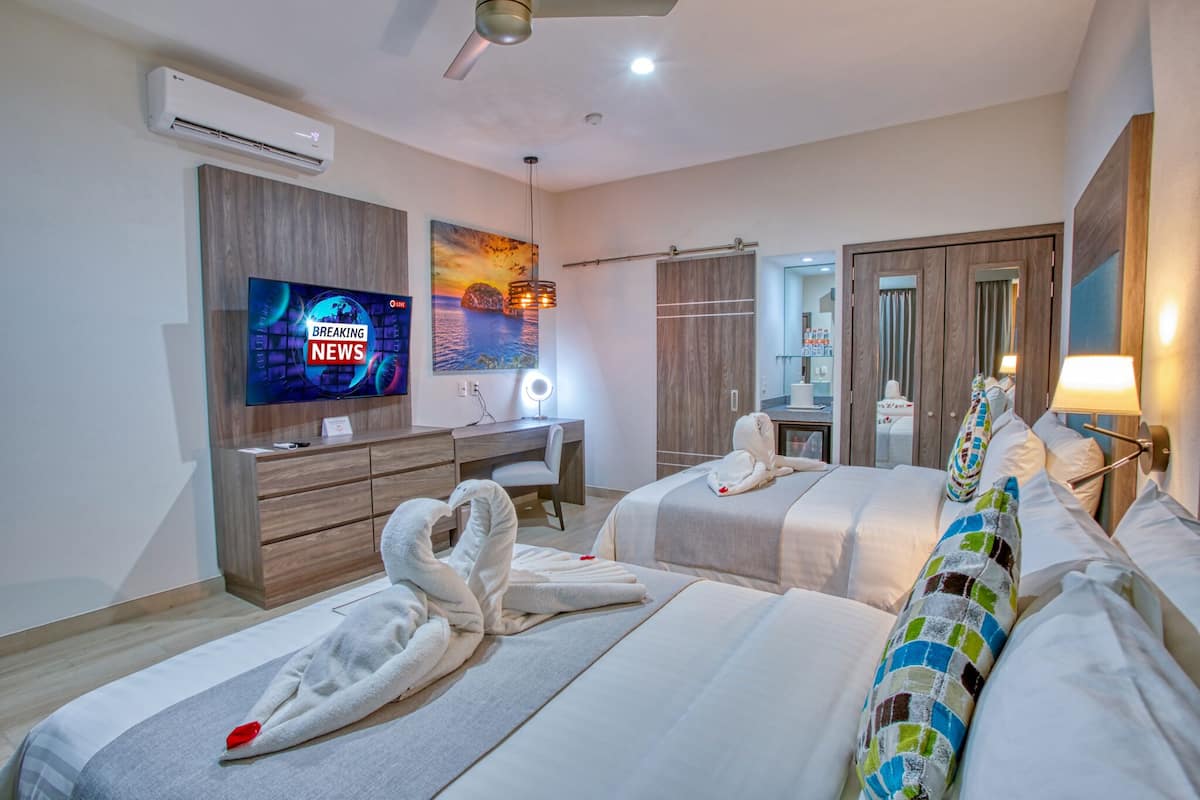 A hotel room with two beds, a desk, a TV, and a painting.