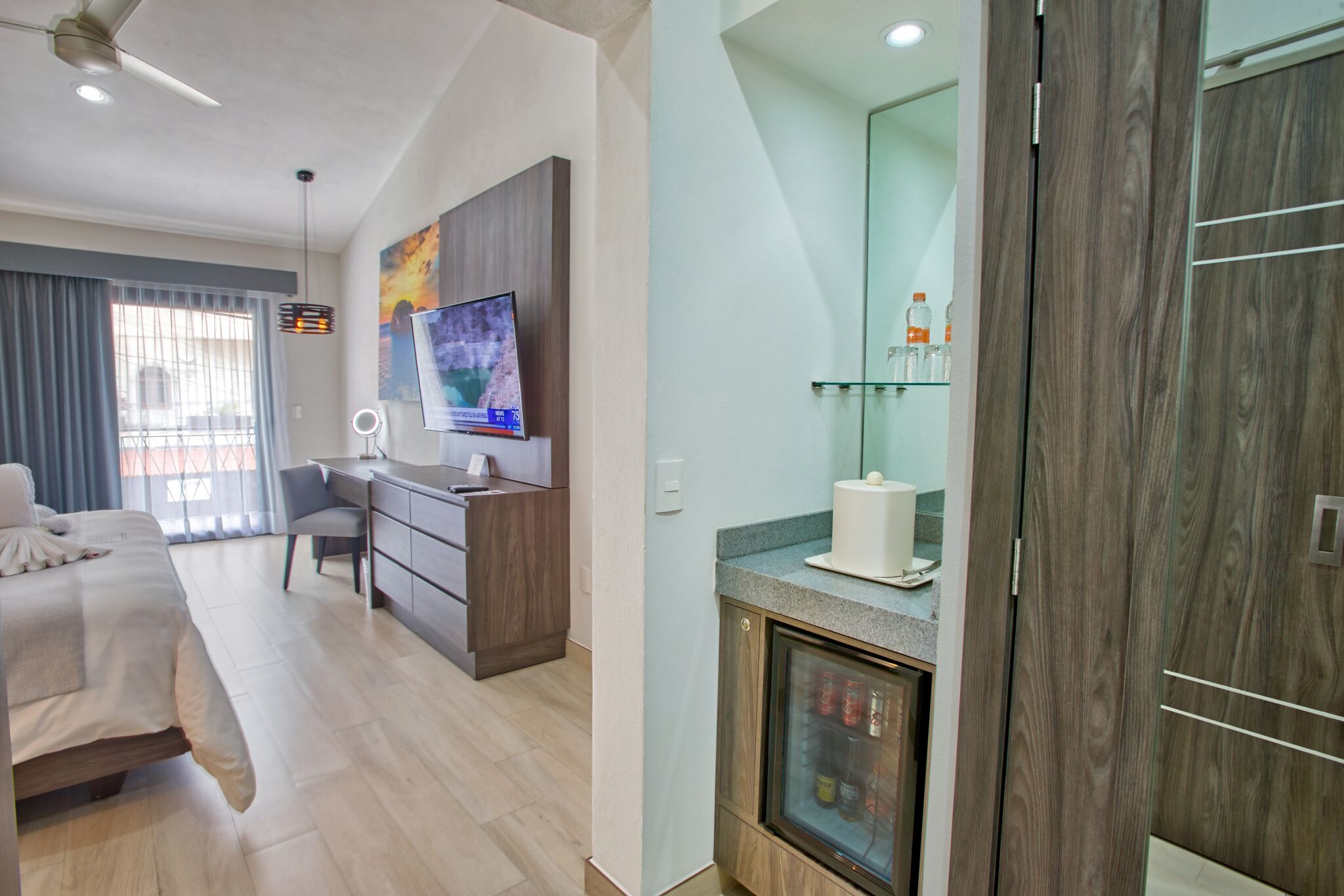 Una habitación de hotel moderna con cama, escritorio y televisor.