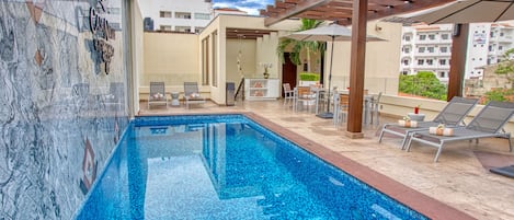 A swimming pool with lounge chairs and a pergola.