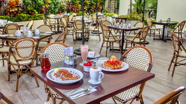 An outdoor dining area with wicker chairs and tables, surrounded by lush greenery. - Casa Nicole Boutique Hotel (Puerto Vallarta)