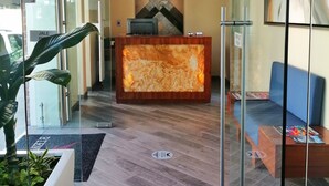 A reception area with a wooden reception desk, a television, and a modern chandelier. - Casa Nicole Boutique Hotel (Puerto Vallarta)