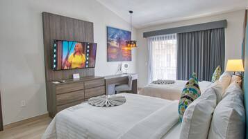 Quarto de hotel com duas camas, uma escrivaninha, uma televisão e uma janela com cortinas.