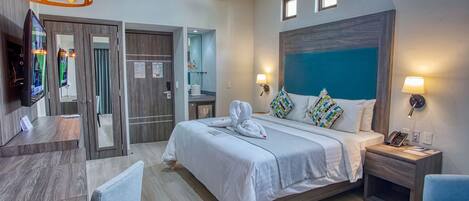A hotel room with a bed, bedside tables, a desk, and a TV.