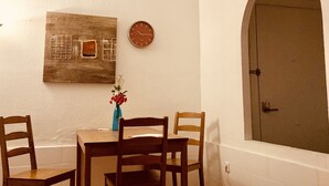 Ein Essbereich mit Tisch und Stühlen, einer Uhr, einer Blumenvase, einem Deckenventilator und einem Heizgerät.