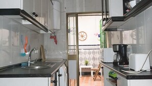 Eine schmale Küche mit weißen Schränken, einer schwarzen Arbeitsplatte und einer Kaffeemaschine.