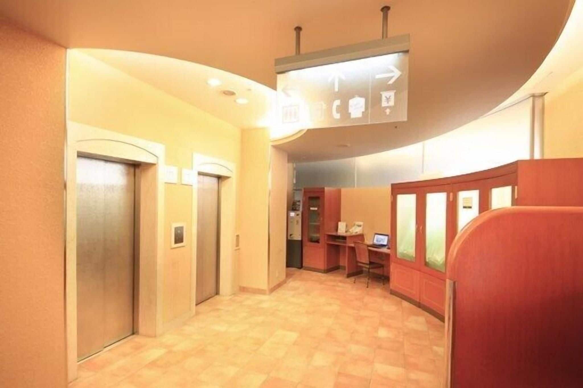 Un vestíbulo de hotel con ascensores, una recepción y un área de descanso.