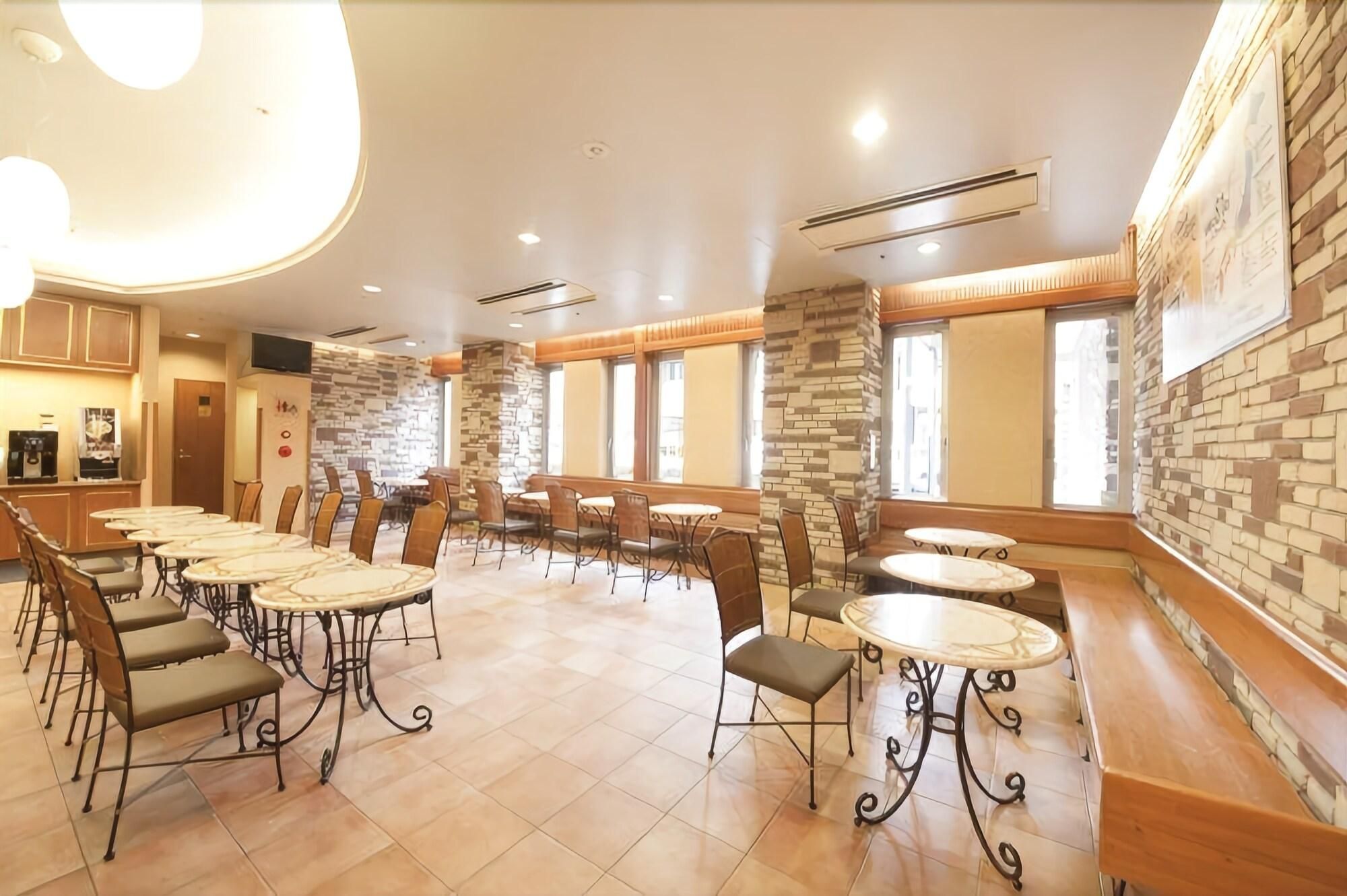 A hotel dining area with multiple tables and chairs, stone accent walls, and large windows.