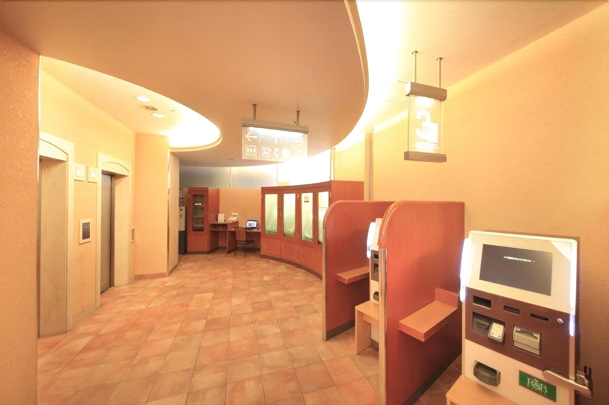 Un couloir d’hôtel comprenant un espace de réception, un kiosque en libre-service et un coin salon.