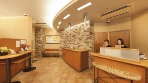 A reception area with a curved counter, a stone wall, and a bench. - R&B Morioka-ekimae (Morioka)