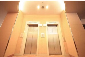 An elevator with two doors, a light fixture above, and a wall-mounted control panel. - R&B Morioka-ekimae (Morioka)