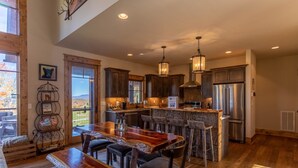 A spacious kitchen with wooden cabinets, a large island, and a stainless steel refrigerator. - Red, White and Views at Eagles Nest- club amenities, hot tub, long range views, pet friendly (Banner Elk)
