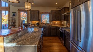 A spacious kitchen with dark wooden cabinets, a stainless steel refrigerator, and a granite countertop. - Red, White and Views at Eagles Nest- club amenities, hot tub, long range views, pet friendly (Banner Elk)