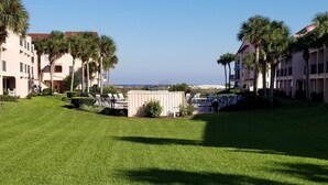 A well-maintained lawn with a small fenced area, palm trees, and buildings with balconies. - 2 Bed, 2 Bath, Ocean View, Poolside - Sea Place 13137 (St. Augustine)