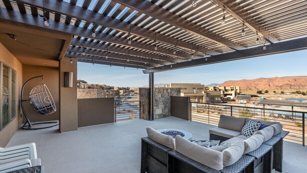 A rooftop patio with a seating area, a hanging chair, and a view of the surrounding landscape. - Oasis by the Pool (St. George)