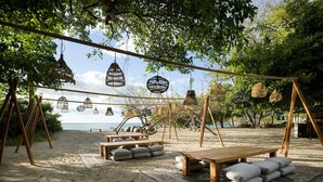 An outdoor seating area with wooden tables and benches, surrounded by hanging birdcages and a view of the sea. - Oceanview Escape in Peninsula Papagayo – Pool, Concierge & Resort Access (Peninsula Papagayo)