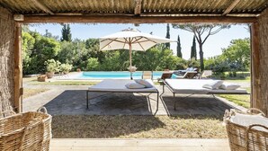 An outdoor pool area with lounge chairs and a pergola.