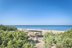 Ein Strand mit einer Holzpergola und Liegestühlen.