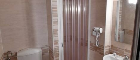 A bathroom with a toilet, a shower, and a sink.