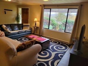 A living room with a sofa, coffee table, lamp, and a TV. - South Hills Rose house (Eugene)