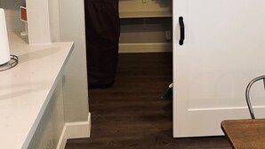 Une pièce de taille modeste dotée d’un placard à porte coulissante, d’un plan de travail blanc et d’un plancher en bois.
