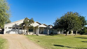Une maison de plain-pied avec un garage, une véranda et une pelouse bien entretenue.
