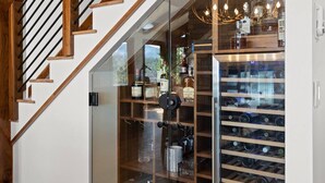 A modern staircase with wooden railings and a wine rack with bottles. - Modern Mountain Lake House - 3 bedrooms + Master Loft (Polson)