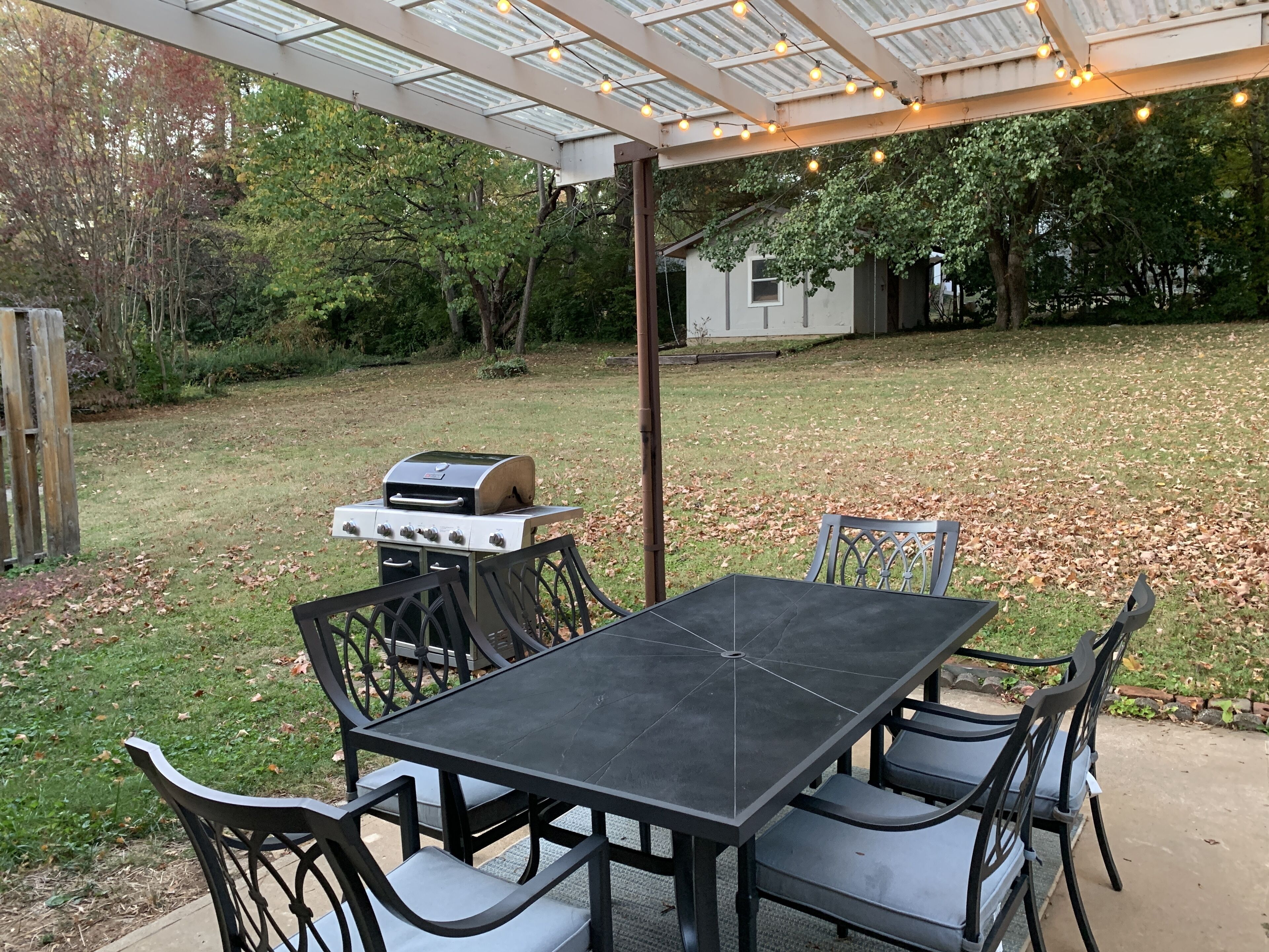 Un patio al aire libre con una parrilla, una mesa y sillas.