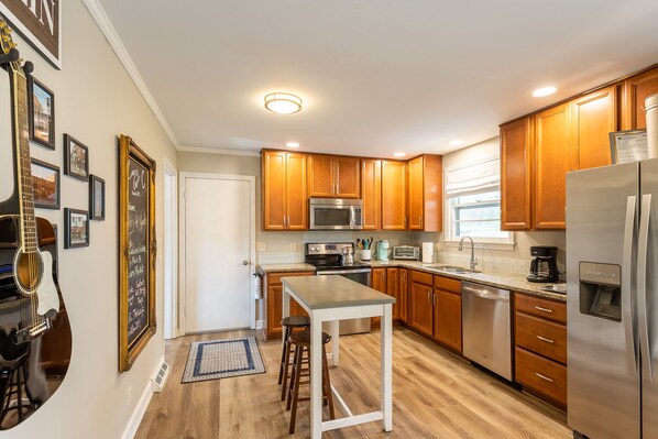 A kitchen with wooden cabinets, a stainless steel refrigerator, a microwave, and a coffee maker. - Stay in Franklin - Close to downtown - fire pit & grill (Franklin)