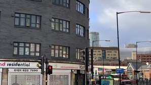 A multi-story building with a curved facade, featuring a commercial ground floor with signage for residential services and a contact number. - Birmingham city centre apartment  (Birmingham)